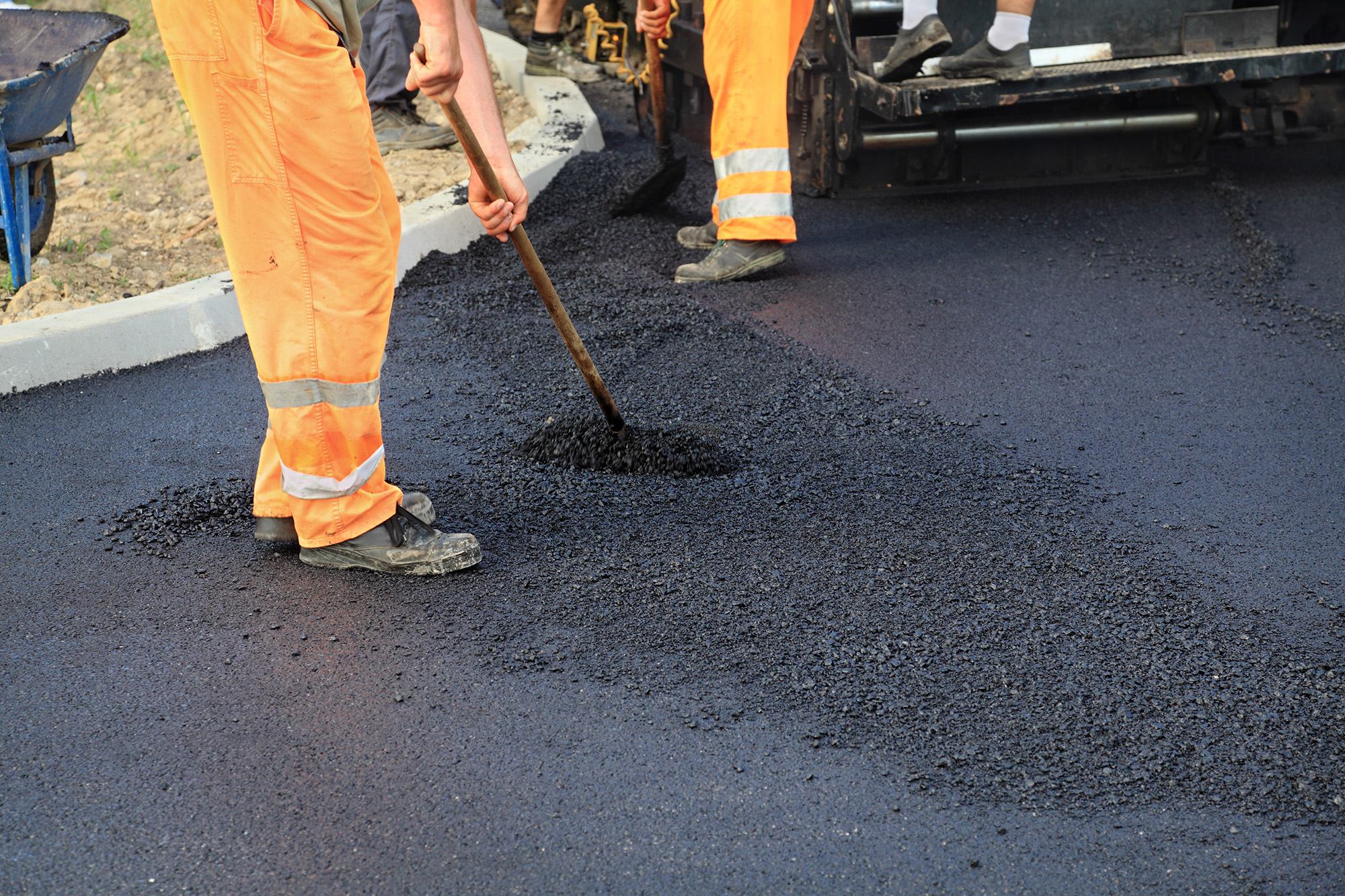 Workers making asphalt with shovels at road construction